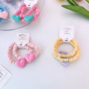 Vue détaillée des chouchous plissés pastel avec breloques cœur sur cartes de support