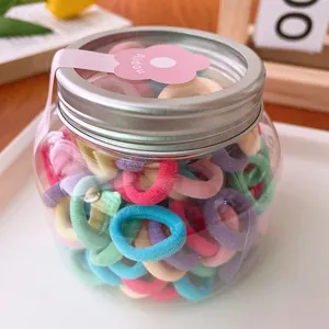 Jar of candy-colored mini elastic hair ties for kids with bright macaron color tones
