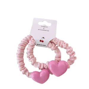 Lot de deux chouchous roses à volants avec grands charms cœur sur carte blanche