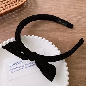 Detailed macro view of black velvet bow headband with a Hand-Made label on lace plate