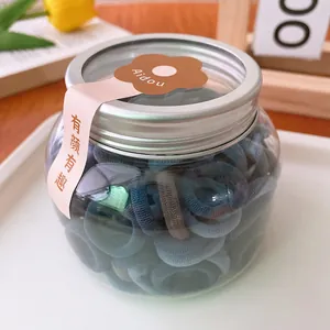 Detailed view of colorful elastic hair bands in a transparent jar with silver lid