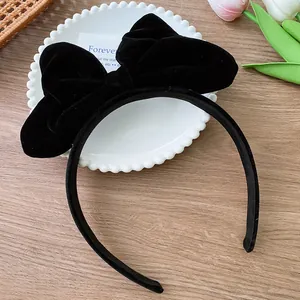 Detail of the oversized black velvet bow headband on a wooden background for girls
