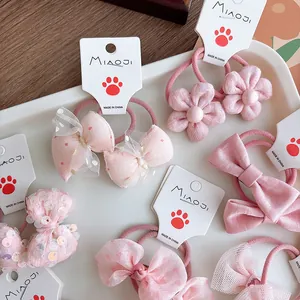 Close-up of pink bow hair ties with sequins, mesh, and pearls for girls on white cards