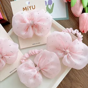 Pink seersucker bow hair tie and clip set with silver dots on a white tray