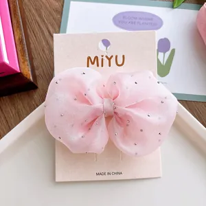 Pink seersucker bow hair clip with silver rhinestones on a display card