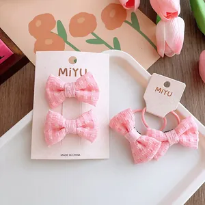 Dettaglio di fermagli per capelli con fiocco rosa e elastici su un supporto bianco