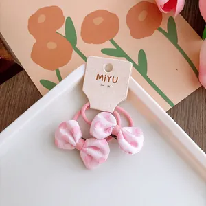 Dettaglio di elastici per capelli con fiocchi rosa a pois su scheda di supporto