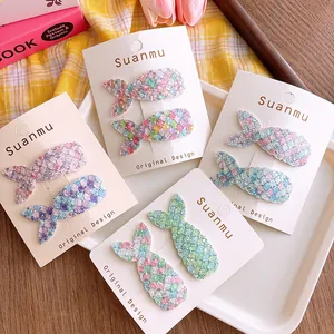 Detail of glitter mermaid tail hair clips with colorful sequins on white display card