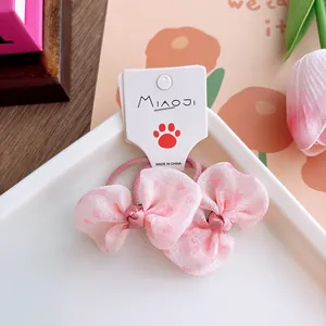 Detailed view of pink chiffon bow hair ties with heart patterns on display card