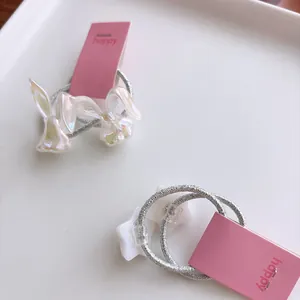 Detailopname van parelmoer konijn en ster haarelastiekjes op een roze displaykaart