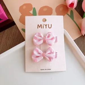 Dettaglio di fermagli per capelli con fiocchi rosa a pois per bambine su carta decorata