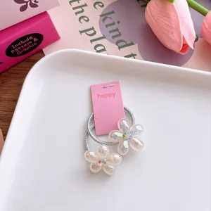 Detailopname van twee parelmoer bloemen met strasstenen op een roze displaykaart