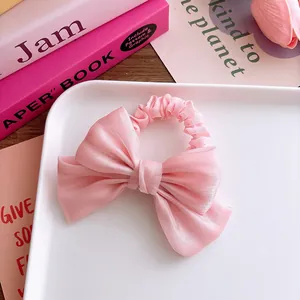 Detail von süßem rosa Tüll-Haargummi mit Schleife und sanftem Glanz auf Tablett