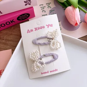 Vue détaillée de barrettes à nœuds en perles faites main sur tissu violet et carte