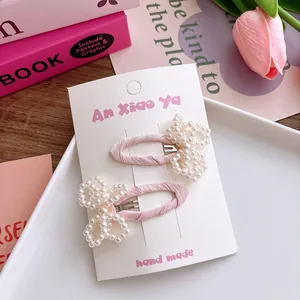 Détail de barrettes faites main en tissu rose doux avec nœuds décoratifs en perles blanches