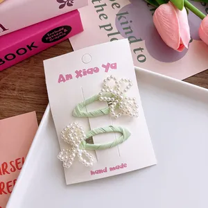Détail de barrettes vertes faites à la main avec de jolis nœuds en perles blanches