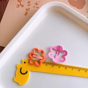 Detail of 3cm hollow flower hair clips in pink and orange with ruler for size reference