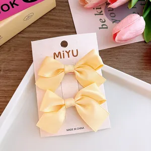 Detail of two yellow ribbon bow hair clips on display card with floral background