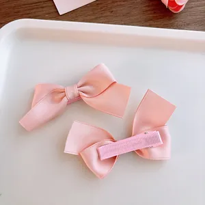 Close-up of pink satin bow hair clips with soft fabric-wrapped clips for girls