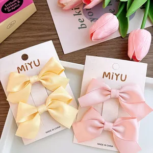 Detailed view of sweet pastel fabric bow hair clips in pink and yellow silk ribbons