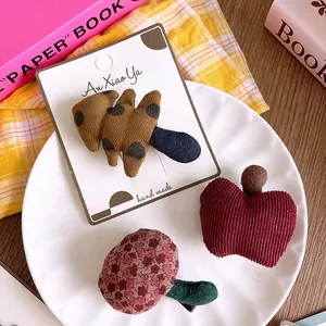 Detalle de tres pinzas para el cabello hechas a mano en tela con motivos de frutas y dibujos