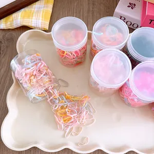 Detail of colorful elastic hair bands in clear jars on a cream tray with warm background