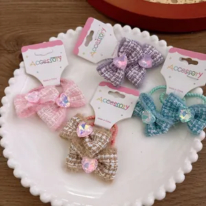 Detail of four tweed bow hair ties with heart gems on a decorative white plate