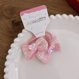 Close-up of pink tweed bow hair ties with iridescent heart gem on display card