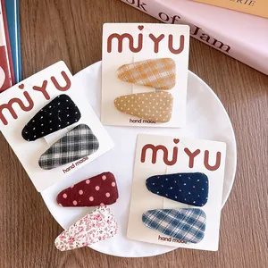 Detail view of handmade fabric hair clips in assorted patterns on a white display card