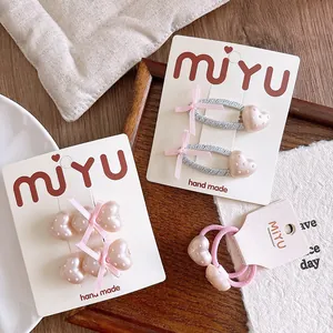 Dettaglio di fermagli per capelli rosa con cuori, pois e fiocchi su cartoncini