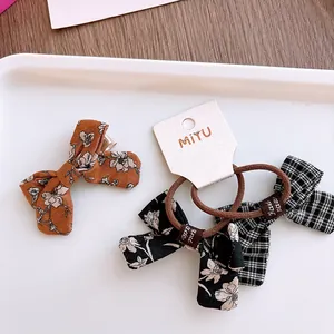 Set van bloemen en geruite stoffen haarstrikken met oranje bloesems en labels