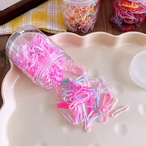Detail of colorful macaron elastic hair bands in a transparent container on pink tray