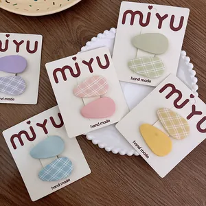 Detalle de cinco pares de pinzas para el cabello de tela a cuadros de colores para niñas