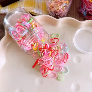 Close-up of colorful elastic hair bands scattered from a clear storage jar on a tray