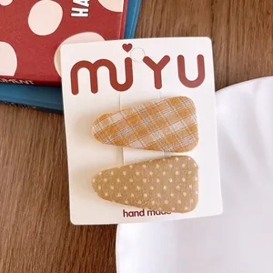 Close-up of handmade yellow plaid and polka dot fabric wrapped hair clips on a card