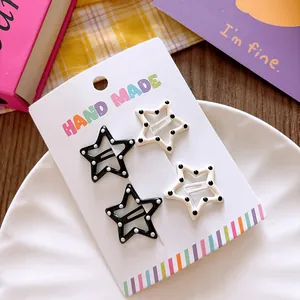 Detailed view of four star-shaped hair clips with polka dots on a handmade display card