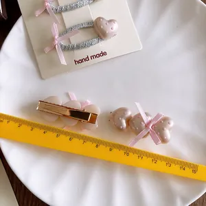 Set di fermagli per capelli rosa con perle a pois e fiocchi di seta su piatto bianco
