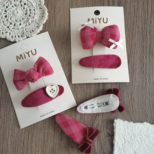 Dettaglio dei fermagli per capelli con fiocco in tessuto rosa e clip BB in velluto