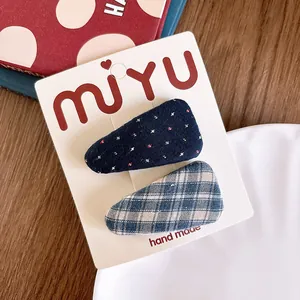 Detail of fabric hair clips with blue cross-stitch and classic plaid patterns on display card