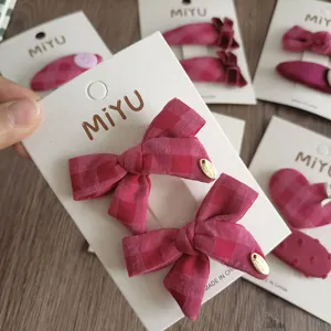 Dettaglio di fermagli per capelli a fiocco a scacchi rosa fatti a mano su supporto