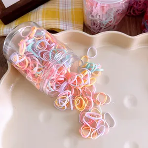 Macro view of colorful elastic hair bands in a transparent jar on a cream tray