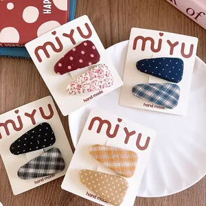 Detailed close-up of handmade fabric BB hair clips in floral and plaid patterns
