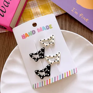 Set of four butterfly hair clips with polka dots on a handmade card in a styled layout