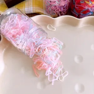 Colorful elastic hair bands pouring from a clear storage jar on a decorative tray