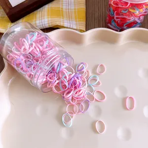 Colorful elastic hair bands poured from a clear jar onto a cream tray for kids
