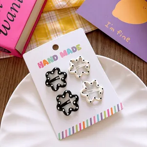 Close-up of four floral hair clips with polka dots on a handmade cardboard display