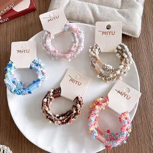 Lot de chouchous tissés colorés pour enfants, présentés sur cartes sur une table en bois