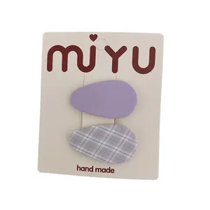 Juego de dos pinzas para el cabello de tela morada con diseño liso y de cuadros