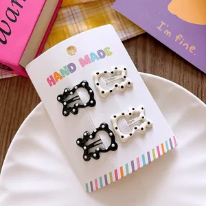 Close-up of four geometric wave hair clips with polka dots on a display card