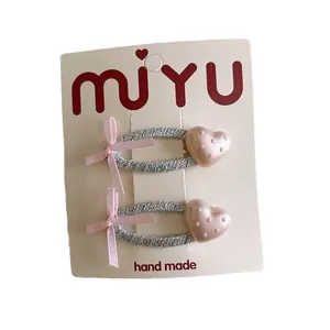 Set di due fermagli per capelli rosa con cuori a pois e fiocchi per bambine su carta